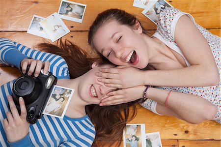 eyes shut - Girls lying on floor with camera, surrounded by photographs Stock Photo - Premium Royalty-Free, Code: 614-06974395