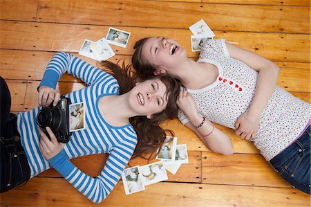 simsearch:614-06974366,k - Girls lying on floor with camera, surrounded by photographs Foto de stock - Royalty Free Premium, Número: 614-06974396