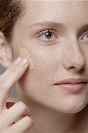 simsearch:614-06974550,k - Close up of part of young woman's face, applying concealer Stock Photo - Premium Royalty-Free, Code: 614-06974556