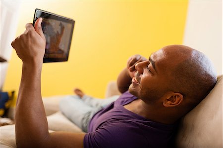 Mid adult male on sofa holding digital tablet and mobile phone Stock Photo - Premium Royalty-Free, Code: 614-06974768
