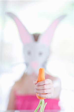 Girl in rabbit costume eating carrot Stock Photo - Premium Royalty-Free, Code: 614-06973554