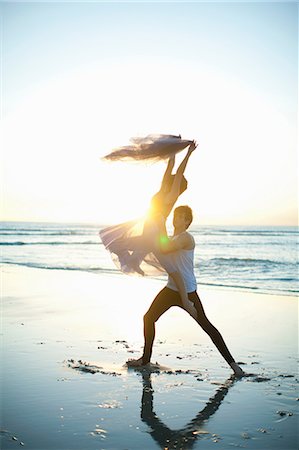 Young man lifting dancing partner on sunlit beach Stock Photo - Premium Royalty-Free, Code: 614-06973613