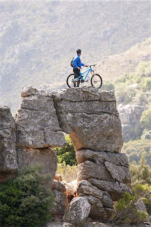 success mountain - Young man standing on rock formation with mountain bike Stock Photo - Premium Royalty-Free, Code: 614-06973757