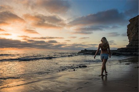 simsearch:649-06812732,k - Young woman walking on beach at sunset, rear view Stock Photo - Premium Royalty-Free, Code: 614-06973889