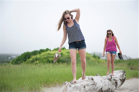 Young women walking along log on beach Stock Photo - Premium Royalty-Free, Code: 614-07031114