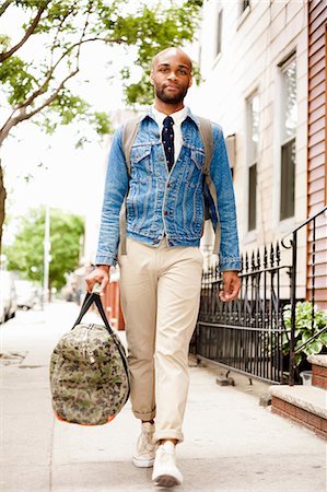 Young man walking down street with holdall Foto de stock - Sin royalties Premium, Código: 614-07031113