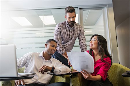 smiling brunette man looking at laptop - Young business colleagues looking at documents in meeting Stock Photo - Premium Royalty-Free, Code: 614-07031140