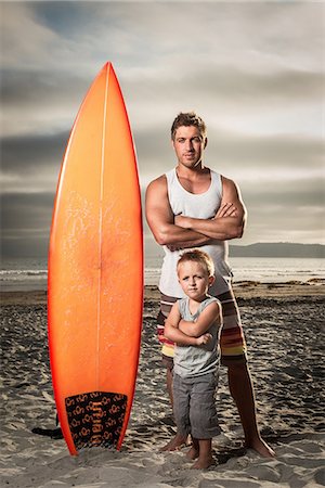 Young man and son standing with surfboard on beach, portrait Stock Photo - Premium Royalty-Free, Code: 614-07031182