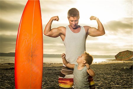 family beach photo - Young man and son flexing muscles on beach Stock Photo - Premium Royalty-Free, Code: 614-07031183