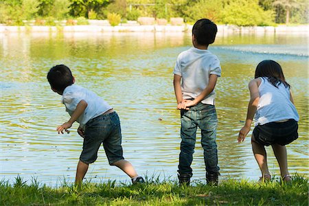 preteen girls backsides - Three children playing by lake Stock Photo - Premium Royalty-Free, Code: 614-07031211