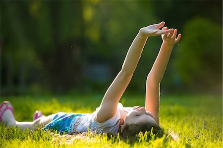 Girl lying on grass with arms raised Photographie de stock - Premium Libres de Droits, Code: 614-07031233