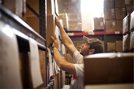 simsearch:640-06963544,k - Worker reaching up for cardboard box stored in warehouse Stock Photo - Premium Royalty-Free, Code: 614-07031311