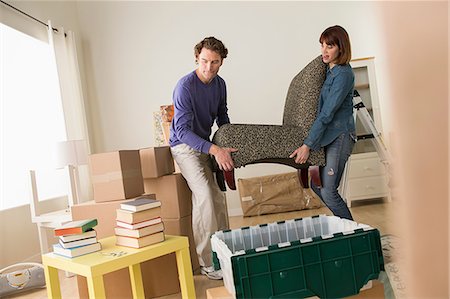 Couple lifting chair in house move Foto de stock - Royalty Free Premium, Número: 614-07031326