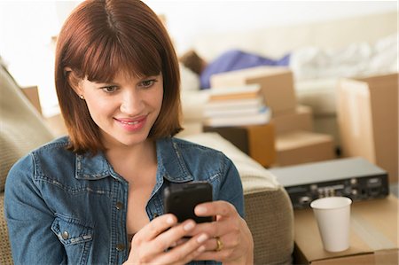 sharing a drink - Woman texting on cellphone whilst moving house Stock Photo - Premium Royalty-Free, Code: 614-07031341