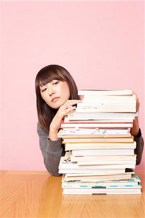simsearch:614-02838643,k - Mid adult woman looking at stack of books on desk Stock Photo - Premium Royalty-Free, Code: 614-07031446