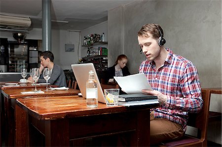 Young man wearing headphones with laptop in cafe Photographie de stock - Premium Libres de Droits, Code: 614-07031544