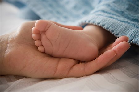 ethnic newborn with mom - Mid adult woman holding baby boy's foot Stock Photo - Premium Royalty-Free, Code: 614-07031692