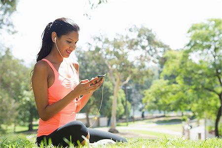 peach color - Young woman listening to mp3 player in park Stock Photo - Premium Royalty-Free, Code: 614-07031773