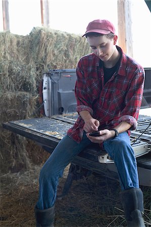 farmer at barn - Young farmer sitting and using mobile phone Stock Photo - Premium Royalty-Free, Code: 614-07031797