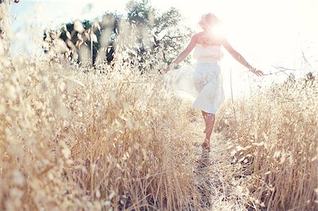 peaceful woman alone - Woman walking through field touching grasses Stock Photo - Premium Royalty-Free, Code: 614-07031820