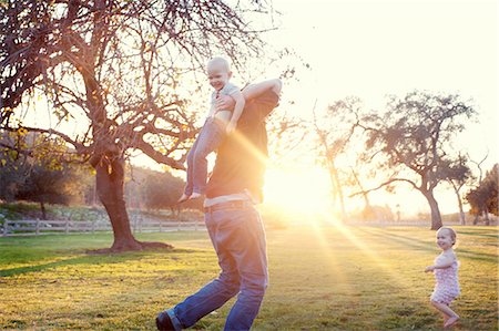 father walk with daughter - Father carrying son in sunlit field Stock Photo - Premium Royalty-Free, Code: 614-07031877