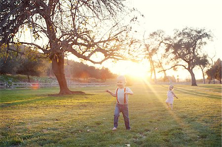 Brother and sister playing in sunlit field Stock Photo - Premium Royalty-Free, Code: 614-07031878