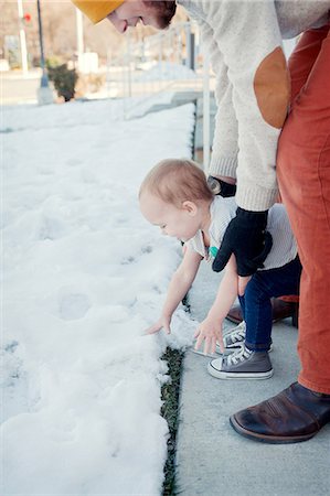 Young girl touching snow with father watching Stock Photo - Premium Royalty-Free, Code: 614-07031889