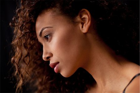 Young woman in profile against black background Stock Photo - Premium Royalty-Free, Code: 614-07031937