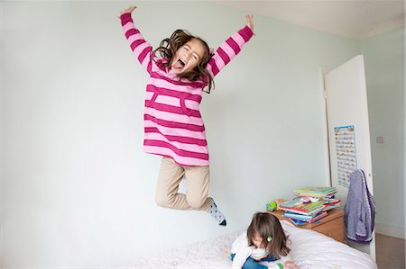 Girl jumping on bed and pulling face Photographie de stock - Premium Libres de Droits, Code: 614-07032029