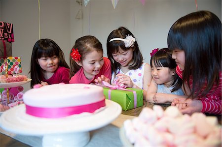 east asian ethnicity girl cake - Girl unwrapping birthday present at party Stock Photo - Premium Royalty-Free, Code: 614-07032051