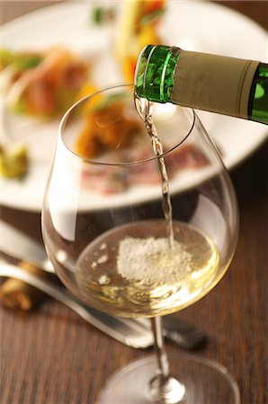 Still life of white wine pouring into glass Stock Photo - Premium Royalty-Free, Code: 614-07032088