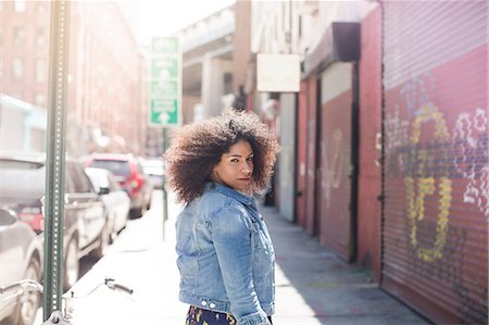 Young woman walking down street looking over shoulder Photographie de stock - Premium Libres de Droits, Code: 614-07145791