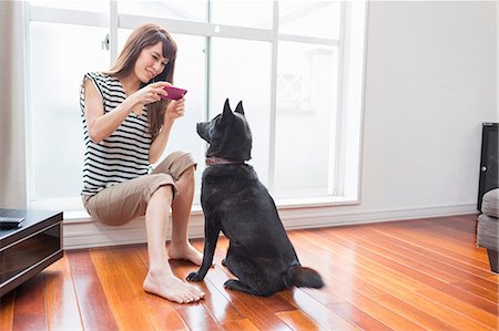 Woman photographing dog on camera phone Stock Photo - Premium Royalty-Free, Code: 614-07145872