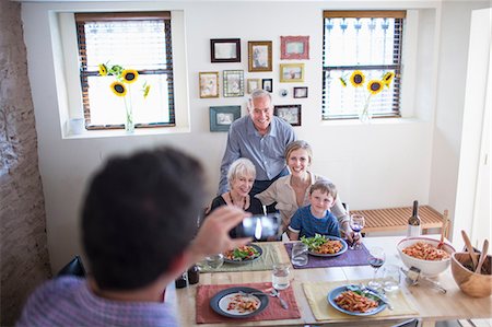 famille élargie - Man photographing family at meal time Photographie de stock - Premium Libres de Droits, Code: 614-07145922