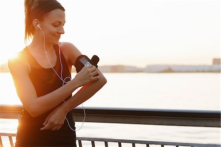 east river - Young female jogger on riverside adjusting MP3 player Photographie de stock - Premium Libres de Droits, Code: 614-07146055