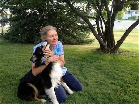 dog licking women photos - Mature woman kneeling on grass with dog, smiling Stock Photo - Premium Royalty-Free, Code: 614-07146081