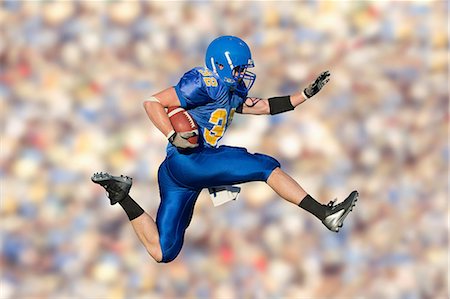 football game - American footballer jumping with ball Stock Photo - Premium Royalty-Free, Code: 614-07146100