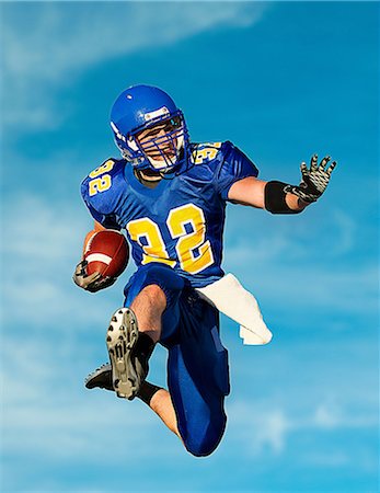 American footballer with ball against blue sky Stock Photo - Premium Royalty-Free, Code: 614-07146110