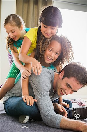 family laughing - Three girls on top of father Stock Photo - Premium Royalty-Free, Code: 614-07146314