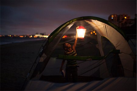 Boy in tent with lap at night, Huntington Beach, California, USA Stock Photo - Premium Royalty-Free, Code: 614-07146375