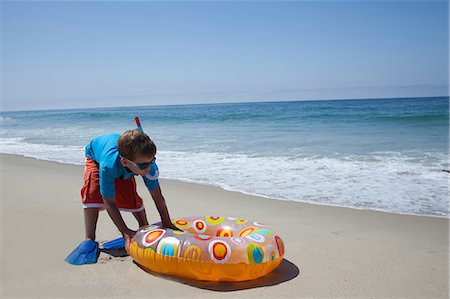 flipper (footwear) - Young boy pushing rubber ring on beach Photographie de stock - Premium Libres de Droits, Code: 614-07146392