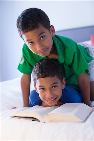 Brothers looking up from book on bed Foto de stock - Sin royalties Premium, Código: 614-07146573