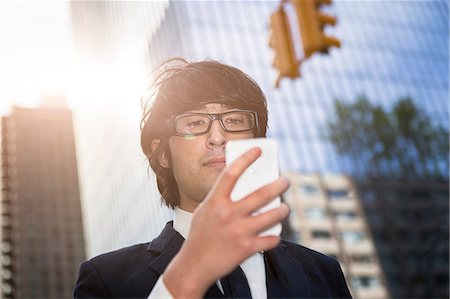 smart phone and texting and business and city - Young businessman using smartphone Foto de stock - Sin royalties Premium, Código: 614-07146638