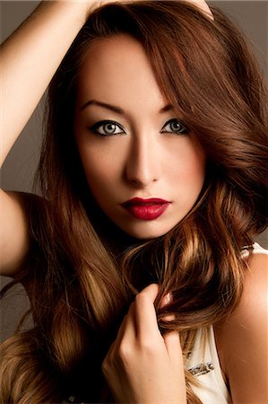 Studio portrait of brunette woman with hands in hair Stock Photo - Premium Royalty-Free, Code: 614-07146700