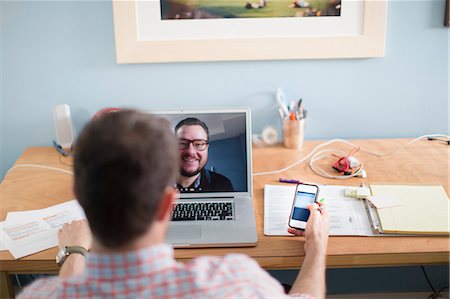 Man sitting at desk making video call Stock Photo - Premium Royalty-Free, Code: 614-07194296