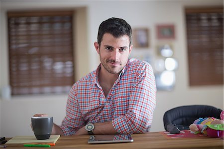 Man sitting at kitchen counter with cup of coffee and digital tablet Stock Photo - Premium Royalty-Free, Code: 614-07194297