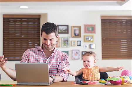 Man working at kitchen counter with baby sitting beside Stock Photo - Premium Royalty-Free, Code: 614-07194300