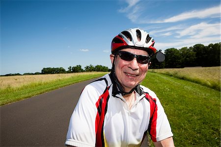 smiling exercise - Senior man riding bicycle through countryside Stock Photo - Premium Royalty-Free, Code: 614-07194430