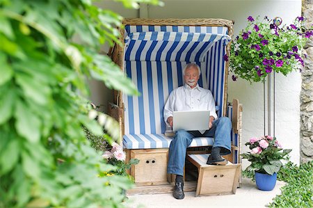 Senior man using laptop on garden seat Stock Photo - Premium Royalty-Free, Code: 614-07194625