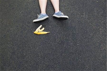 foot in sneakers - Pair of legs and banana skin on tarmac Stock Photo - Premium Royalty-Free, Code: 614-07194719